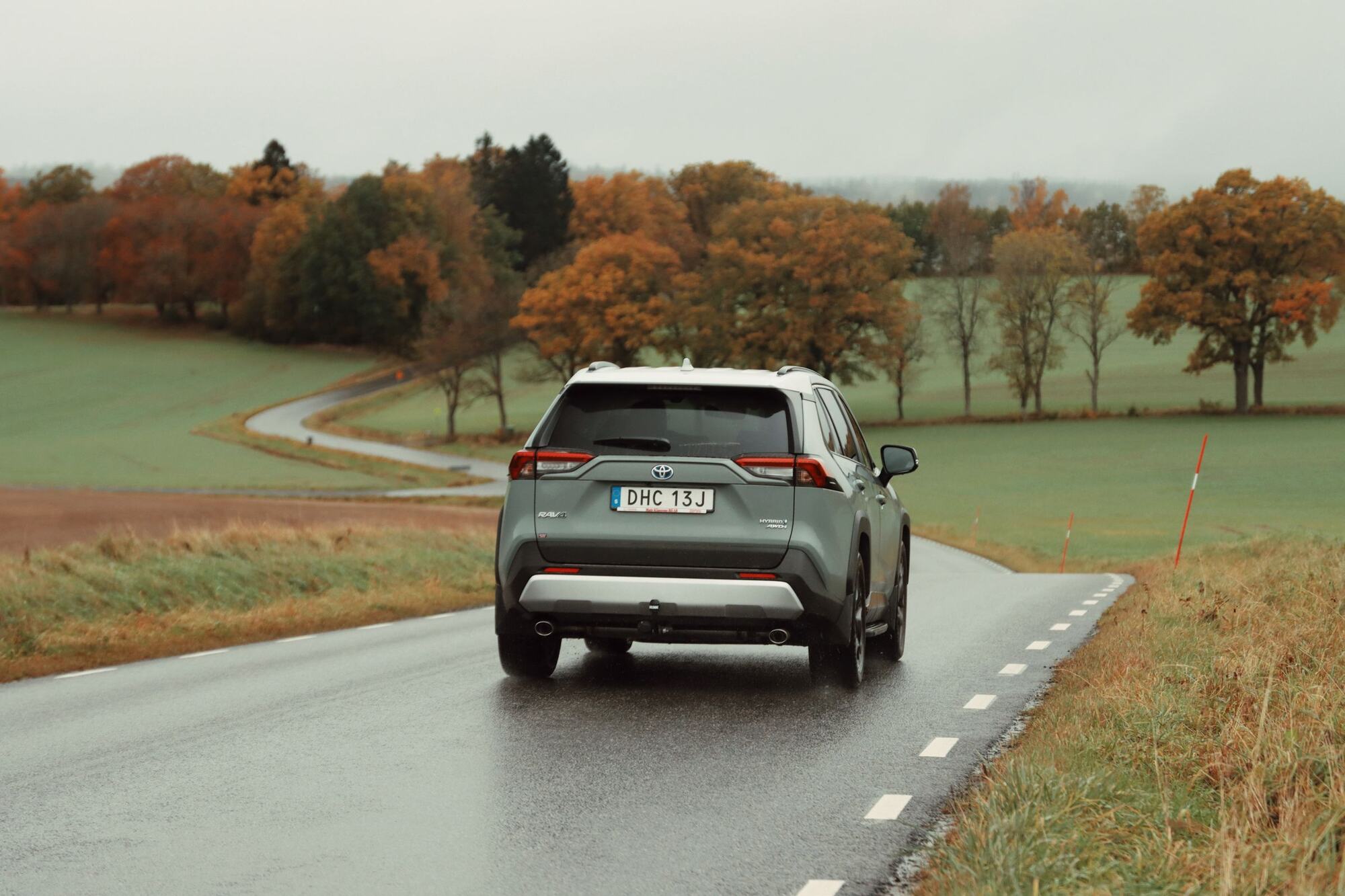 Toyota RAV4 driving away along a tree-lined country road